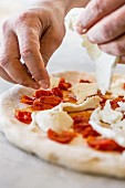 Mozzarella being placed on top of a pizza