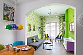 Colourful living area with neon-green wall and patterned wallpaper in retro interior
