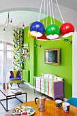 Colourful living area with neon-green wall, painted antique cabinet and brightly coloured, spherical lamps