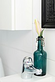 Blume in Vintage Flasche mit Schnappverschluss neben Armatur