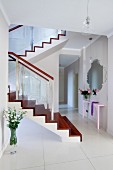 Weisser eleganter Dielenbereich mit glänzendem Fliesenboden und Treppenaufgang mit Setz- und Trittstufen aus Edelholz