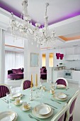 Elegantly set dining table in Neo-Baroque dining area with crystal chandeliers and purple accents