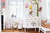 Babybett in Zimmerecke mit Walddeko: stilisierte Baumdarstellung an der Wand und Rehfiguren