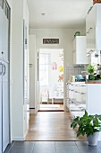 Contemporary kitchen counter with white surfaces; view into child's bedroom through open door