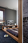 View through open door of designer bed in bedroom with grey wall