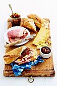 Snack with mango apple chutney, ham, cheese and fresh baguette on rustic wooden board