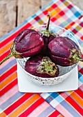 Fresh aubergines in a bowl on a wooden table