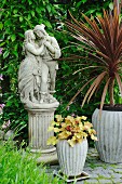 Blumentöpfe um romantisches Figurenpaar auf Sockel im Garten