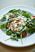 Spinach salad with hummus dressing, tomatoes and nuts