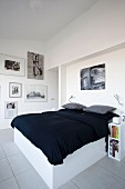 Double bed with white frame and black bedspread in modern bedroom
