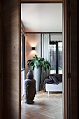 View through open door; head of Buddha, herringbone parquet floor and tall, grey planter in corner