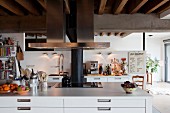 White island counter with drawers and stainless steel extractor hood in loft interior