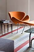 Orangefarbener Retro-Designersessel mit passendem Fussschemel und Beistelltisch im Fiftiesstil