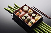 Various sushi in a rectangular tray on a mirrored table