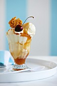 An ice cream sundae with vanilla ice cream, caramel sauce and cherries