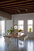 Dining set with classic chairs around table, house plants and vase of tulips in renovated loft apartment