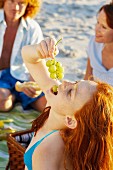 Mädchen isst Trauben beim Strandpicknick