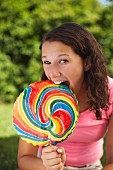 A teenager biting a lollipop