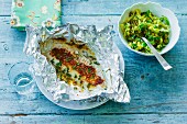 Fish fillet with spices in aluminium foil served with lemon and garlic cabbage