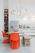 Essplatz mit orangefarbenen Klassikerstühlen, darüber Zettel'z Leuchte von Ingo Maurer in offener Küche