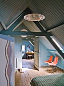 Bedroom in converted attic with wood panelling painted blue and grey