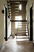 Custom, wood and metal staircase in narrow hallway with herringbone parquet floor