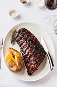 A grilled rack of ribs with a baked potato