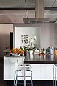 Counter protruding from free-standing, designer kitchen counter with bar stools in loft apartment
