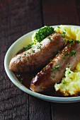 Two sausages with mashed potatoes and beer gravy on a wooden table
