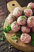 Raw meatballs with parsley on a wooden surface
