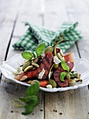 Grilled sausage with a vegetable salad and capers