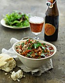 Beef ragout with bread and salad served with a beer