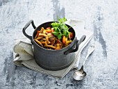Vegetable stew with beef, mushrooms and pasta in a small pot