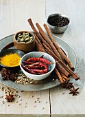 An arrangement of spices featuring cinnamon, cardamom, chillis, star anise, pepper, coriander and turmeric