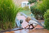 Kleinkind spielt auf gepflastertem Gartenweg