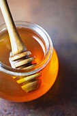 Honig mit Honiglöffel in einem Glas auf Metalluntergrund