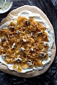 A pizza with cream cheese, caramelised onions and goat's cheese, unbaked