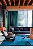 Wink Lounge Chair by Toshiyuki Kita and dark blue sofa in lounge area of loft apartment with glass wall