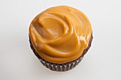 A chocolate cupcake topped with butterscotch pudding