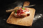 An open ham sandwich on a wooden board