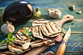 Grilled aubergine slices, garlic and peppermint on a rustic wooden table