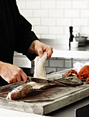 A chef filleting a fish in a kitchen