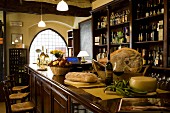 A wheel of cheese and a loaf of bread, wine and Tuscan ham on the bar of an enoteca, Italy