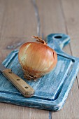 A white onion on a blue chopping board