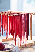 Homemade beetroot pasta drying on a wooden rack