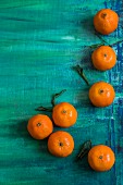 Mehrere Clementinen auf türkisem Untergrund