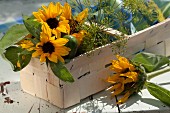 Spankorb gefüllt mit Sonnenblumen und Dillblüten