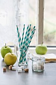 Green apples, sugar cubes and drinking straws in front of a kitchen window