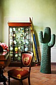 Oversize pencils leaning against display case of globes and cactus sculpture in period apartment