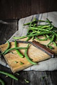 Green beans on a chopping board with a folding knife